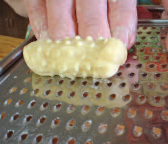 Using a cheese grater to make “goose bumps” on extra pieces of dough for meatless dumplings. We would call these birbizai.